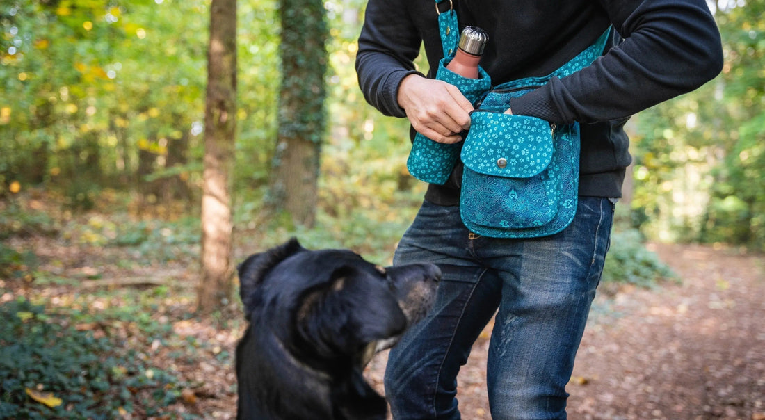 Hundebesitzer mit einer Gassi-Tasche als Geschenkidee in einem Wald mit seinem Hund