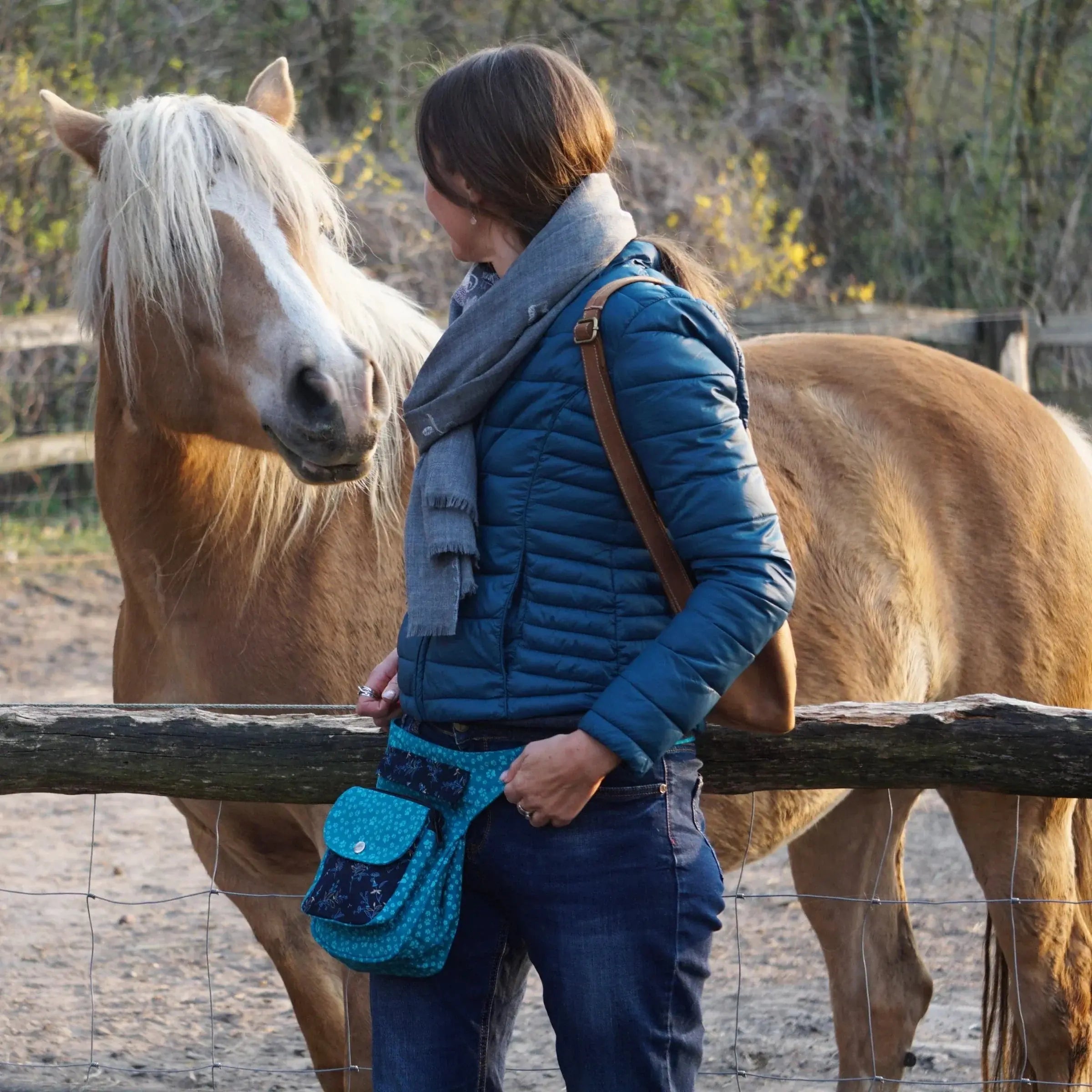 Die Frau mit einer Bauchtasche steht neben einem Pferd.