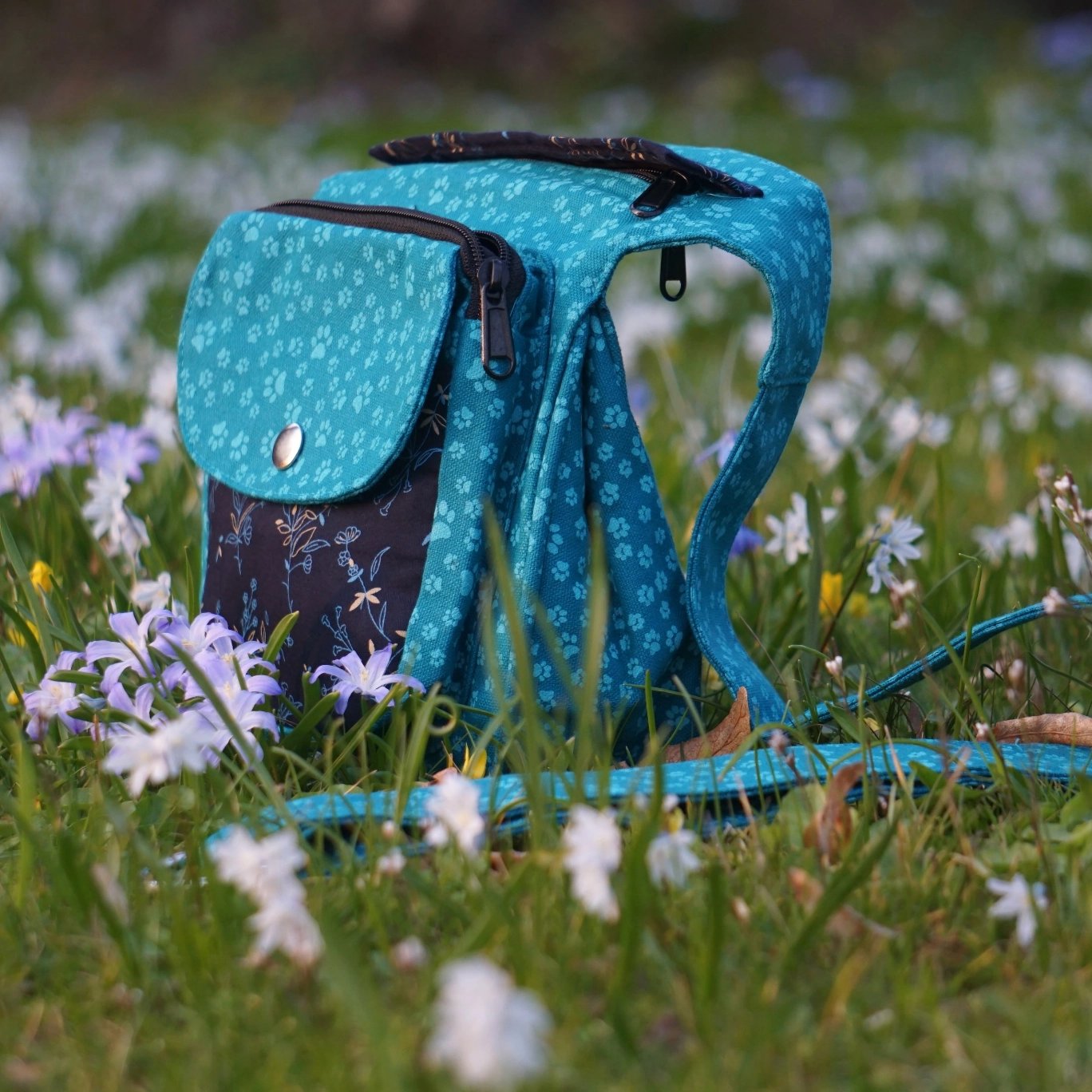 Türkisfarbene Stofftasche mit floralem Muster auf Gras Hintergrund mit Blumen