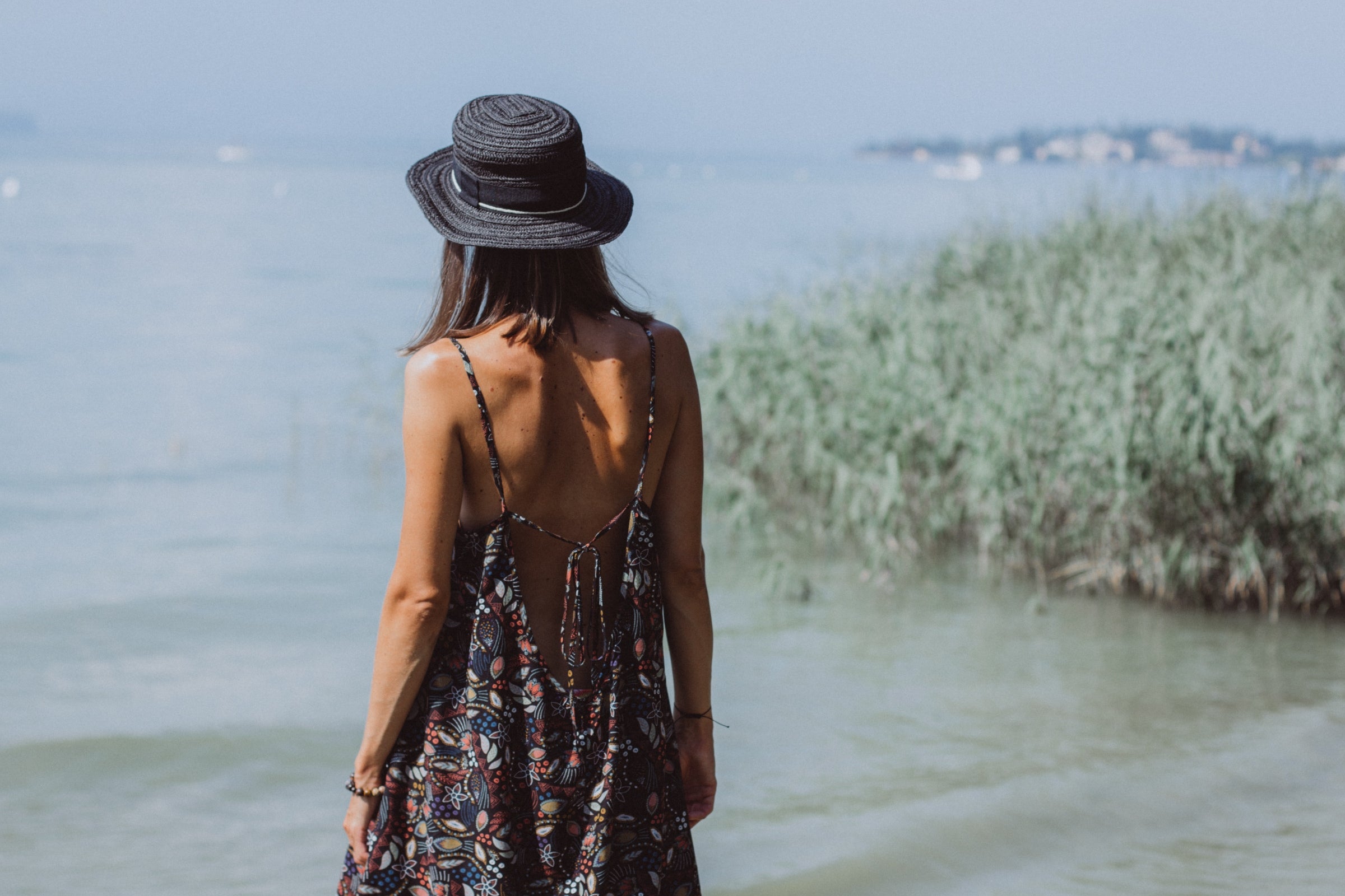 Ein Mädchen im Sommerkleid steht vor einem See