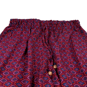 Hose aus Polyester, lila Muster mit elastischen Bund und Kordelzug am Saum . Zwei Holzperlen schmücken die Kordelenden.