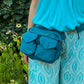 Weibliches Model präsentiert Gassitasche, Bauchtasche sowie Umhängetasche aus Nylon in Türkis.