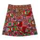 Wickelrock aus Baumwolle, Stoffmix Rot/Grün mit geometrischen Mustern. Der Rock ist von beiden Seiten tragbar. Der Umfang lässt sich mit zwei Druckknopfleisten am Rockbund einstellen. Mit Seitentasche.