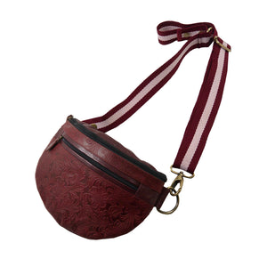 Seitenansicht: Crossbody-Bag sowie Bauchtasche aus Leder in Rot mit floraler Prägung. Das Hauptfach hat ein integriertes Fach mit Reißverschluss und ein Reißverschlussfach vorne.