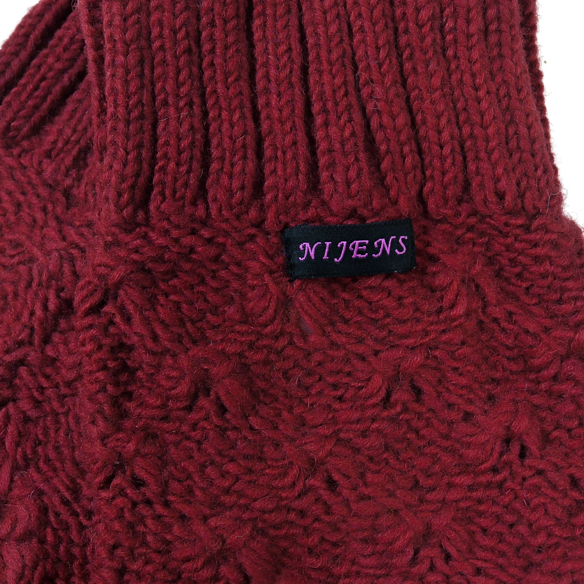 Detailaufnahme der bordeauxroten Woll-Beinstulpen mit Nijens Label