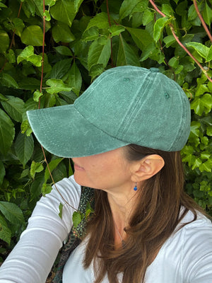 Modell trägt leichte Sommer-Cap in Tannengrün – lässiger Look für warme Tage.