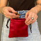 Eine Frau trägt eine rote Leder Leckerli-Tasche mit Karabiner und mit Zugkordel.