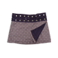 Wenderock aus Baumwolle Lavendel mit sich wiederholendem Muster. Der Rockbund ist aus Kordsamt Violet und ist durch eine doppelte Druckknopfleiste größenverstellbar. An der Seite am Bund, gibt es zwei Metallringe zum Anhängen einer kleinen Stofftasche.