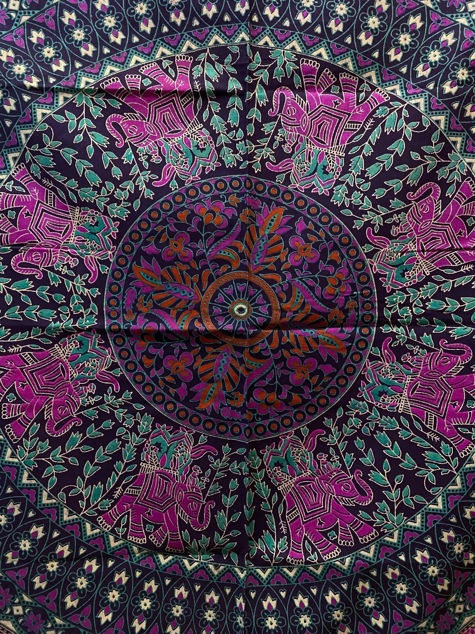 Detailaufnahme einer Mandala-Decke in Lila-Türkis mit floralen Elementen und Elefantenmotiven im Kreisdesign