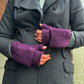 Nahaufnahme Hände: Model präsentiert Fäustlinge, Handstulpen mit Fingerkappe aus Schurwolle Lila. Die Fingerkappe wird mit einem Knopf auf der Handrückenseite fixiert.