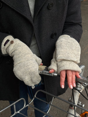 Nahaufnahme Hände: Model präsentiert Fäustlinge, Handstulpen mit Fingerkappe aus Schurwolle Naturweiß. 