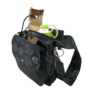 Nijens Gassitasche Hannover aus Canvas-Baumwolle in Schwarz mit floralem Muster, Frontansicht mit Druckknopfklappe, Leckerlifach, Reißverschlussfach mit Trinkflasche und verstellbarem Gurt.