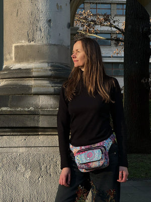 Frau trägt die bunte Mandala-Hüfttasche von Nijens als Crossbody-Bag über der Schulter, im urbanen Lifestyle.