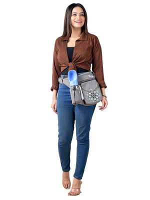 Frau trägt Gassi-Tasche „Brandenburg“ aus Canvas in Grau als Bauchtasche mit Mandala-Stickerei, integriertem Kotbeutelspender und Trinkflaschenhalter