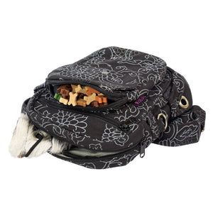 Schwarze Gassitasche mit Blumenmuster geöffnet mit Hundeleckerlis und Trainings-Dummy im Hauptfach – ideal für Hundetraining.