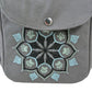 Detailaufnahme einer grauen Nijens Gassitasche mit Mandala-Stickerei in Grau-Türkis und Pfotenmotiv auf der Fronttasche.