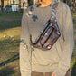 Crossbody Bag Torino mit Mandala-Muster in Blau getragen von Mann im Park mit blühenden Bäumen
