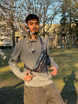 Mann trägt Crossbody Bag Torino mit Mandala-Design im Park bei Frühlingsblüte – praktische Bauchtasche von Nijens