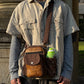 Mann trägt braune Leder Gassi-Tasche Konstanz im Vintage Stil mit Flaschenhalter und geprägtem Muster, als Crossbody Tasche im Alltag
