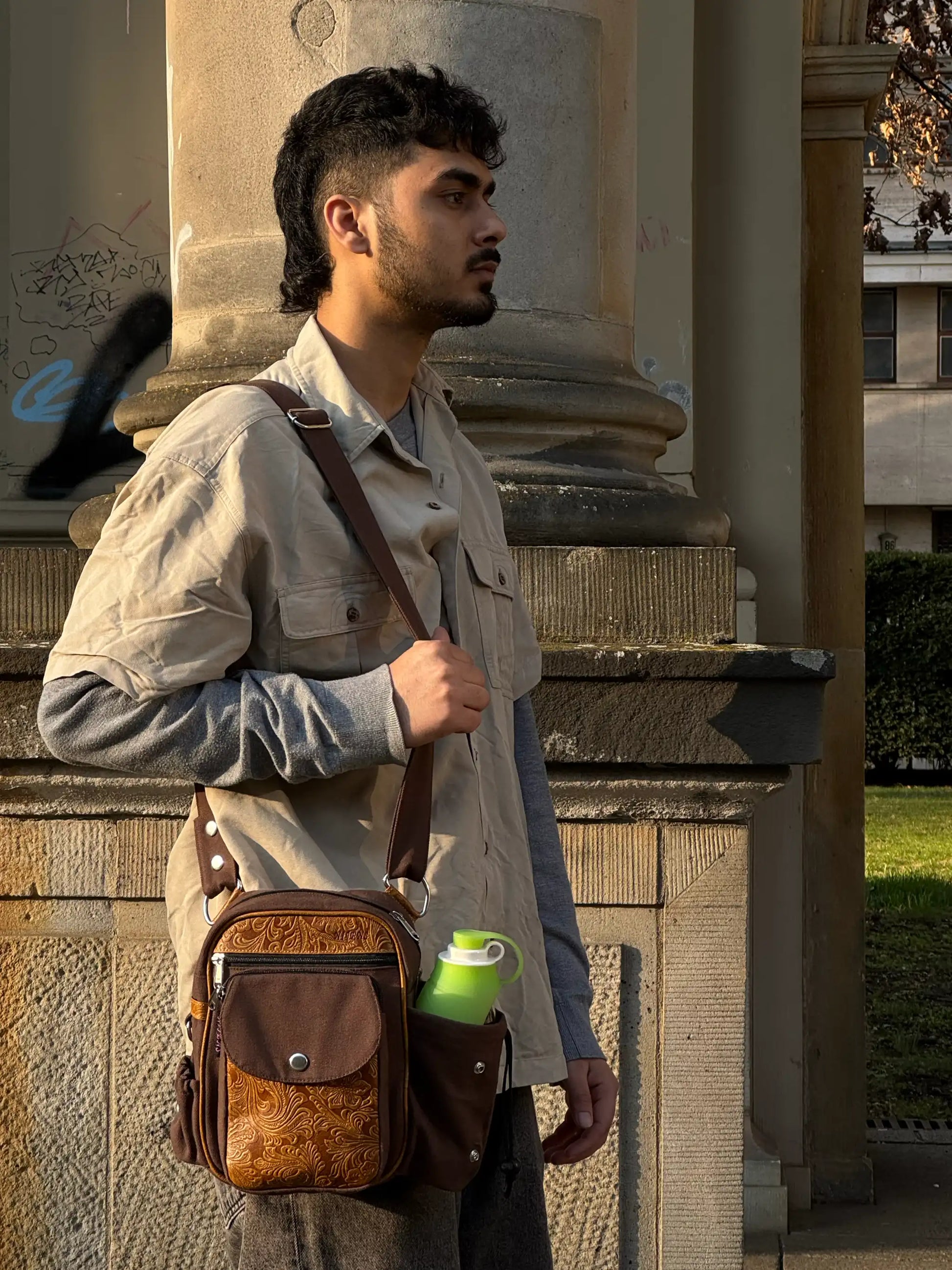 Seitliche Ansicht einer Leder Gassi-Tasche Konstanz mit Trinkflaschenfach, getragen als Schultertasche im urbanen Lifestyle