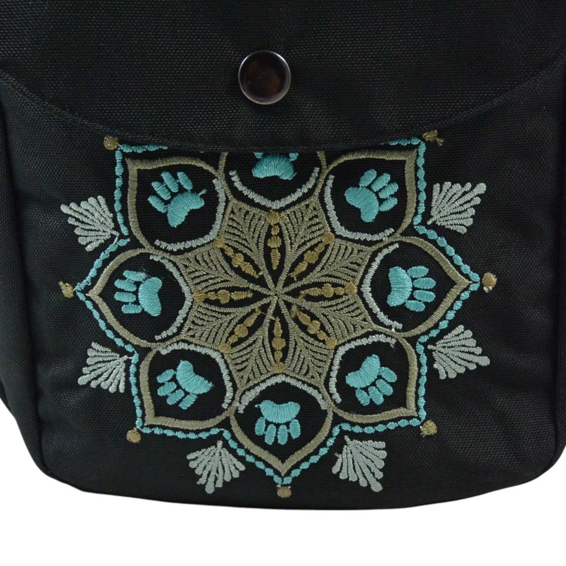 Detailaufnahme einer schwarzen Nijens Gassitasche mit Mandala-Stickerei in Türkis und Pfotenmotiv auf der Fronttasche.