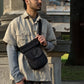 Schwarze Nijens Gassi-Tasche wasserabweisend als Crossbody getragen von Model im Stadtpark