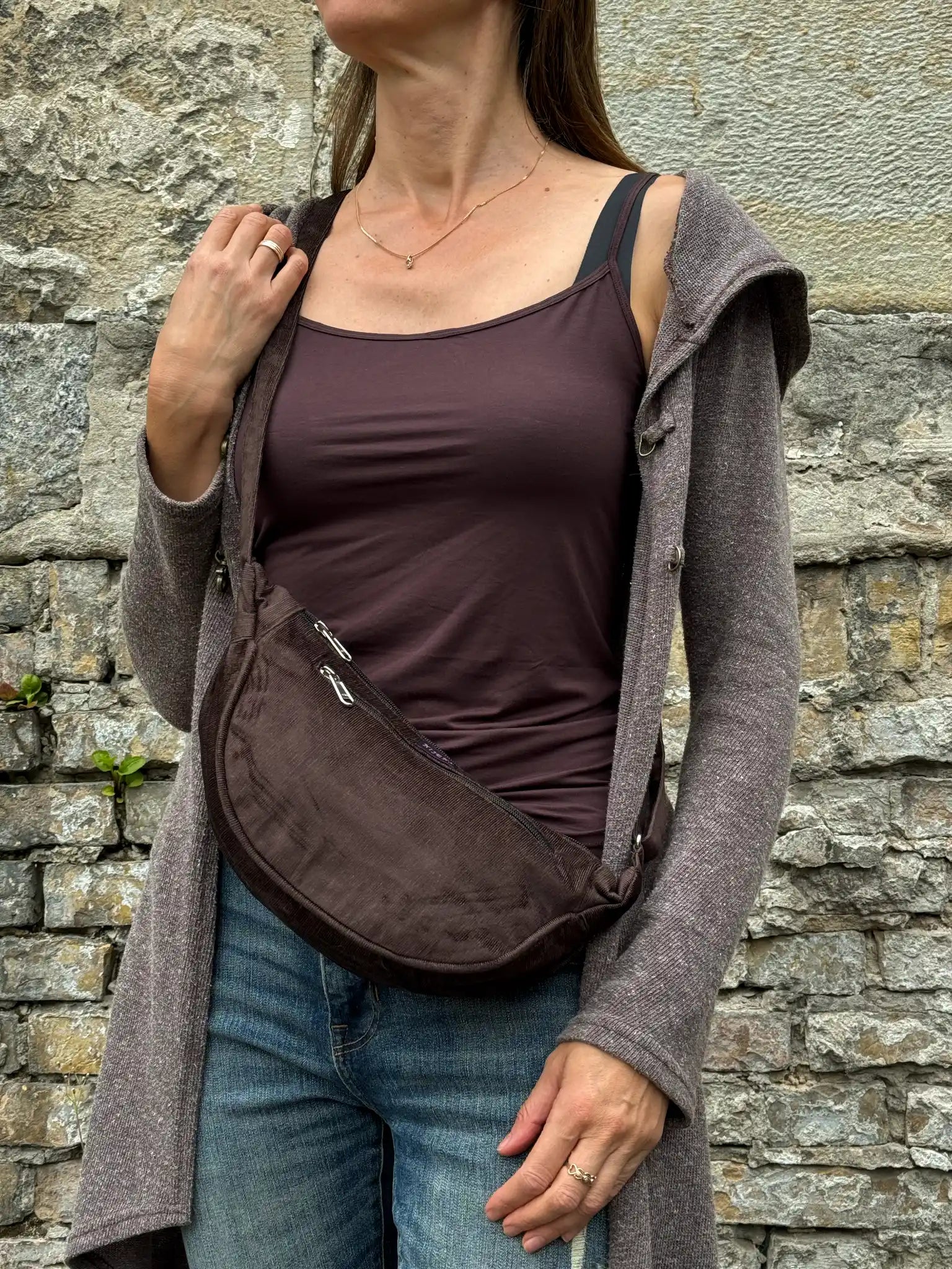 Model präsentiert Schokobraune Cord-Crossbody-Tasche „Rishikesh“ von Nijens in Frontalansicht, mit Reißverschluss und verstellbarem Gurt