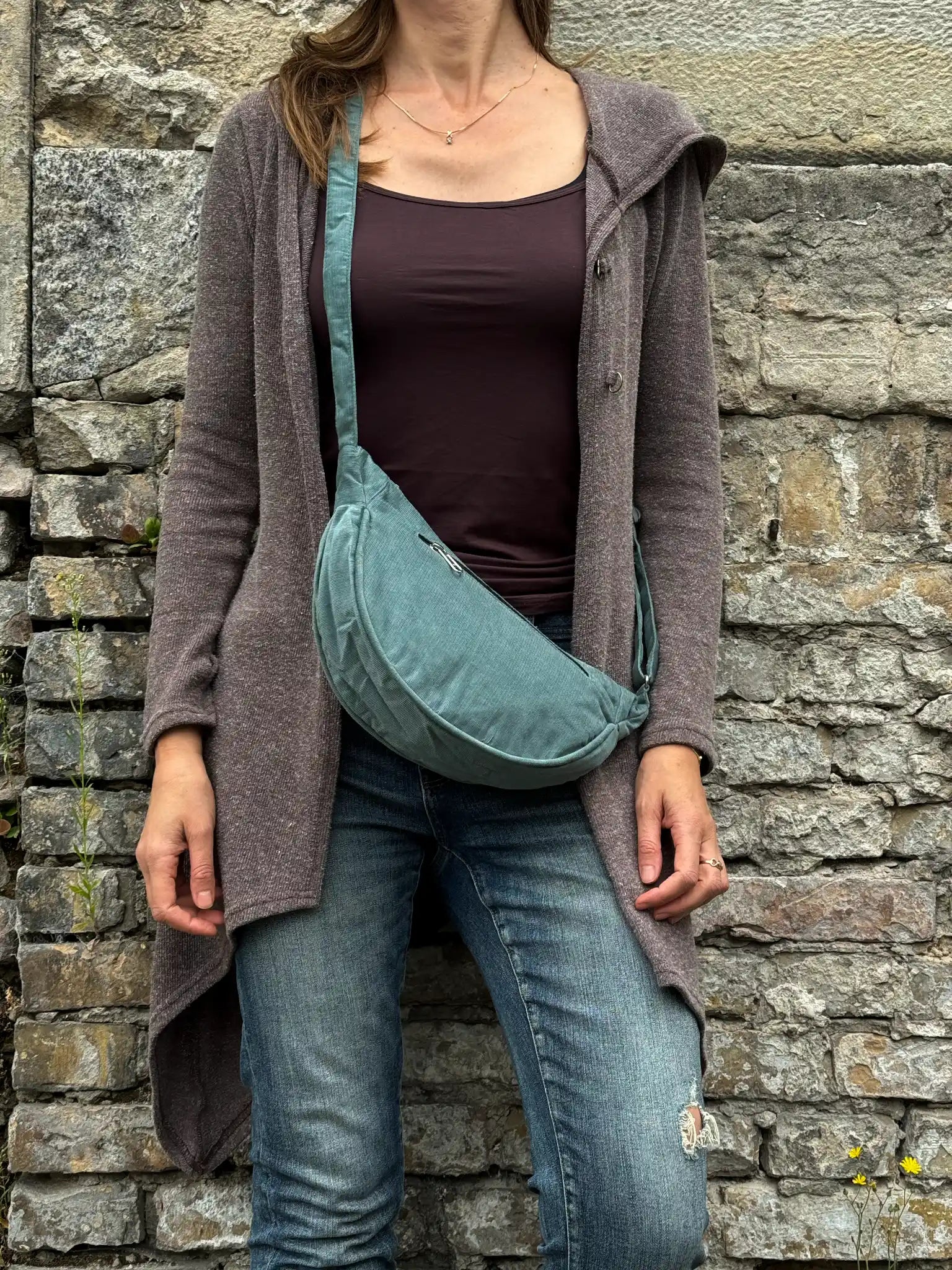 Model präsentiert Crossbodybag „Rishikesh“ aus Cord Salbei von Nijens in Frontalansicht, mit zwei Reißverschlussfächern und verstellbarem Schultergurt