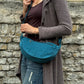 Model trägt Petrolfarbene Crossbodybag „Rishikesh“ aus Cord von Nijens in Frontalansicht, mit zwei Reißverschlussfächern und verstellbarem Schultergurt