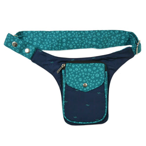 Bauchtasche aus robustem Baumwollstoff in türkis-blau mit Muster und kleinen Pfoten-Print. Diese Gürteltasche besitzt ein Reißverschlussfach vorne sowie ein Einsteckfach, welches durch einen Überschlag und Druckknopf verschlossen wird.