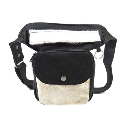 Gürteltasche, Gassi-Tasche in Canvas-Schwarz, Reißverschlussklappe und Vordertasche sind mit weißem Kuhfell und Leder schwarz besetzt. Diese Gürteltasche hat zwei Reißverschlussfächer vorne sowie ein Einsteckfach, welches durch einen Überschlag mit Druckknopf verschlossen wird. 