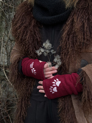 Model präsentiert dunkelrote Handstulpen mit Daumenschlitz aus Schurwolle, bestickt mit zwei Pfoten-Logo.