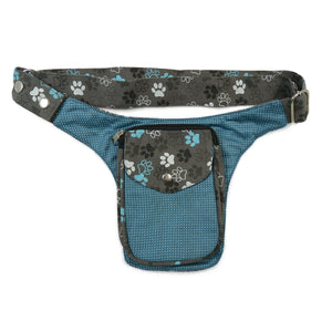 Gassi-Tasche, kleine Bauchtasche aus robustem Baumwollstoff in grau, hellblau mit Muster und großen Pfoten-Print. Diese Gürteltasche besitzt ein Reißverschlussfach vorne sowie ein Einsteckfach, welches durch einen Überschlag und Druckknopf verschlossen wird. 