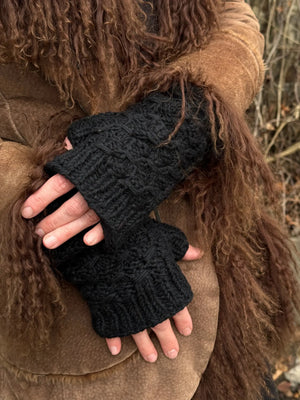 Model präsentiert Handstulpen mit Daumen aus Schurwolle in Schwarz.