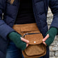 Nahaufnahme: Bauchtasche, Gassi-Tasche aus Cord Olivgrün. Diese Gürteltasche hat zwei Reißverschlussfächer vorne sowie ein Einsteckfach, welches durch einen Überschlag mit Druckknopf verschlossen wird. Auf der hinteren Seite befindet sich ein weiteres Reißverschlussfach. An der Seite des Taschengurtes befindet sich ein kleiner Metallring, zum anhängen kleiner Beuteltaschen.