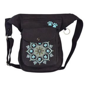 Gassi-Tasche, Bauchtasche und Gürteltasche aus Canvas-Stoff Schwarz mit Pfoten-Mandalastickerei. Diese Gürteltasche hat zwei Reißverschlussfächer vorne sowie ein Einsteckfach, welches durch einen Überschlag mit Druckknopf verschlossen wird. Auf der hinteren Seite befindet sich ein weiteres Reißverschlussfach. An der Seite des Taschengurtes befindet sich ein kleiner Metallring zum Anhängen kleiner Beuteltaschen.