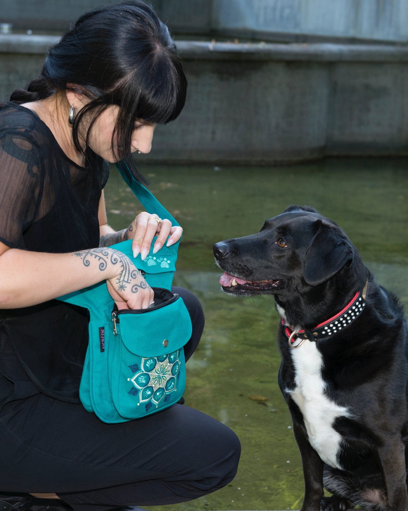 Die Frau nimmt Hundefutter aus einem türkisfarbenen Beutel mit einem schönen Mandala mit Pfotenstickerei.