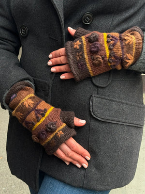 Nahaufnahme Hände: Model präsentiert Handstulpen HEIDRA Set C-12 gestreift aus Schurwolle in Brauntönen und Woll-Stickereien.