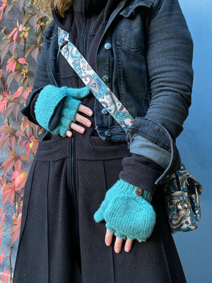 Modell mit Bauchtasche, Umhängetasche aus Stoff, Bunte Mandala-Motive, Beltbag Nijens und Fingerlose Handschuhe aus Schurwolle in Mint mit Fleeceeinlage. Durch eine umklappbare Fingerabdeckung können die fingerlosen Handschuhe auch als Fäustlinge getragen werden.