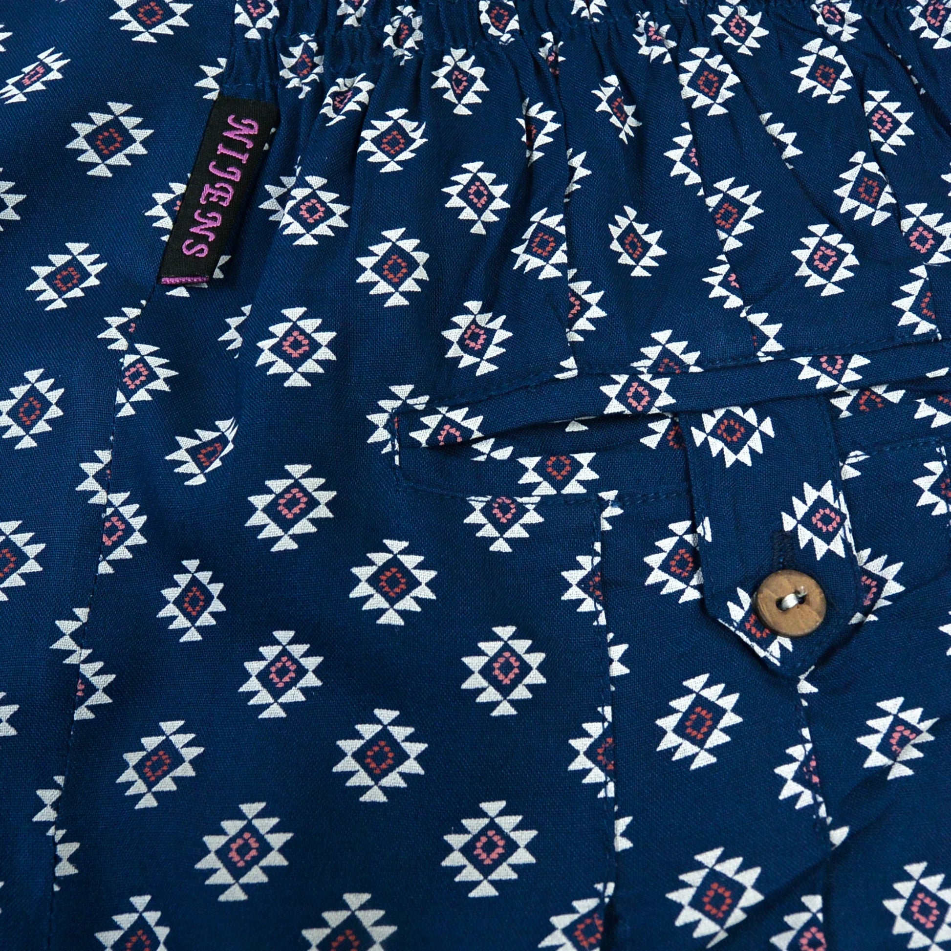 Detailansicht der dunkelblauen Viskosehose mit weiß-rotem Ethno-Muster und Knopftasche von Nijens