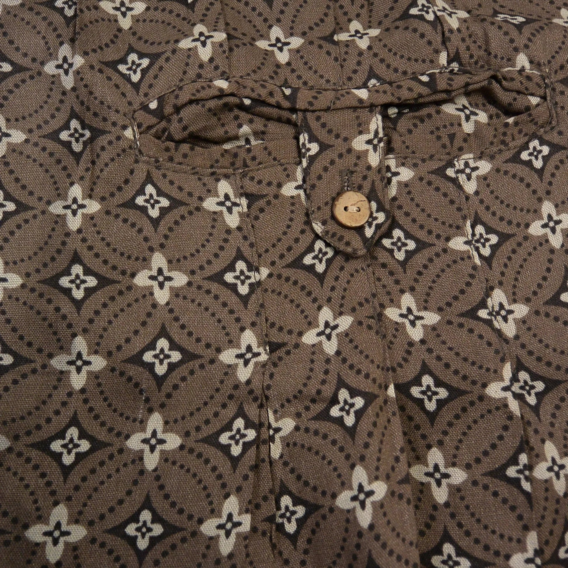 Detailansicht der Knopftasche und des braunen Ethno-Musters der Viskosehose von Nijens.