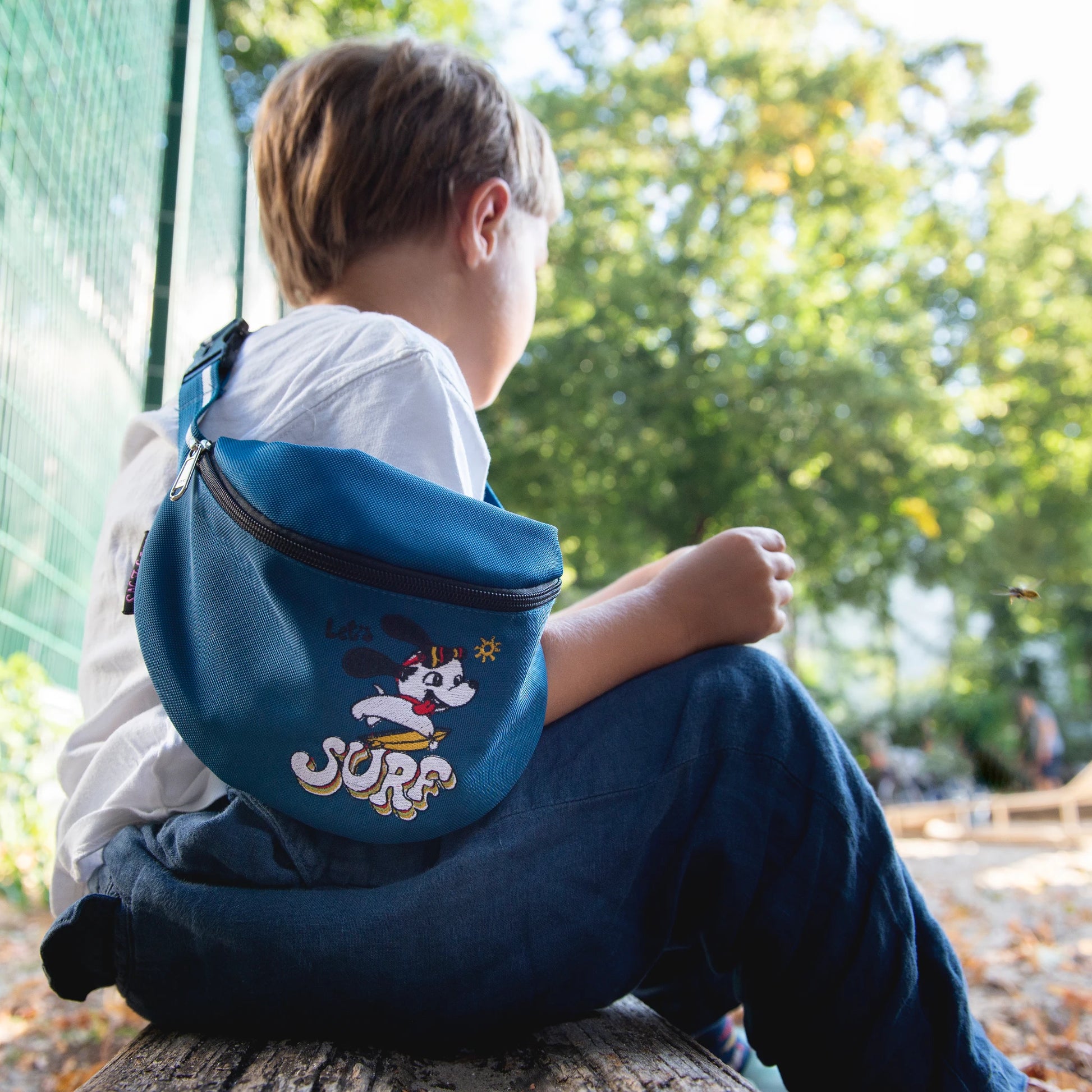 Der Junge trug eine blaue Tasche mit einem Motiv "Let's Surf" auf der Schulter.