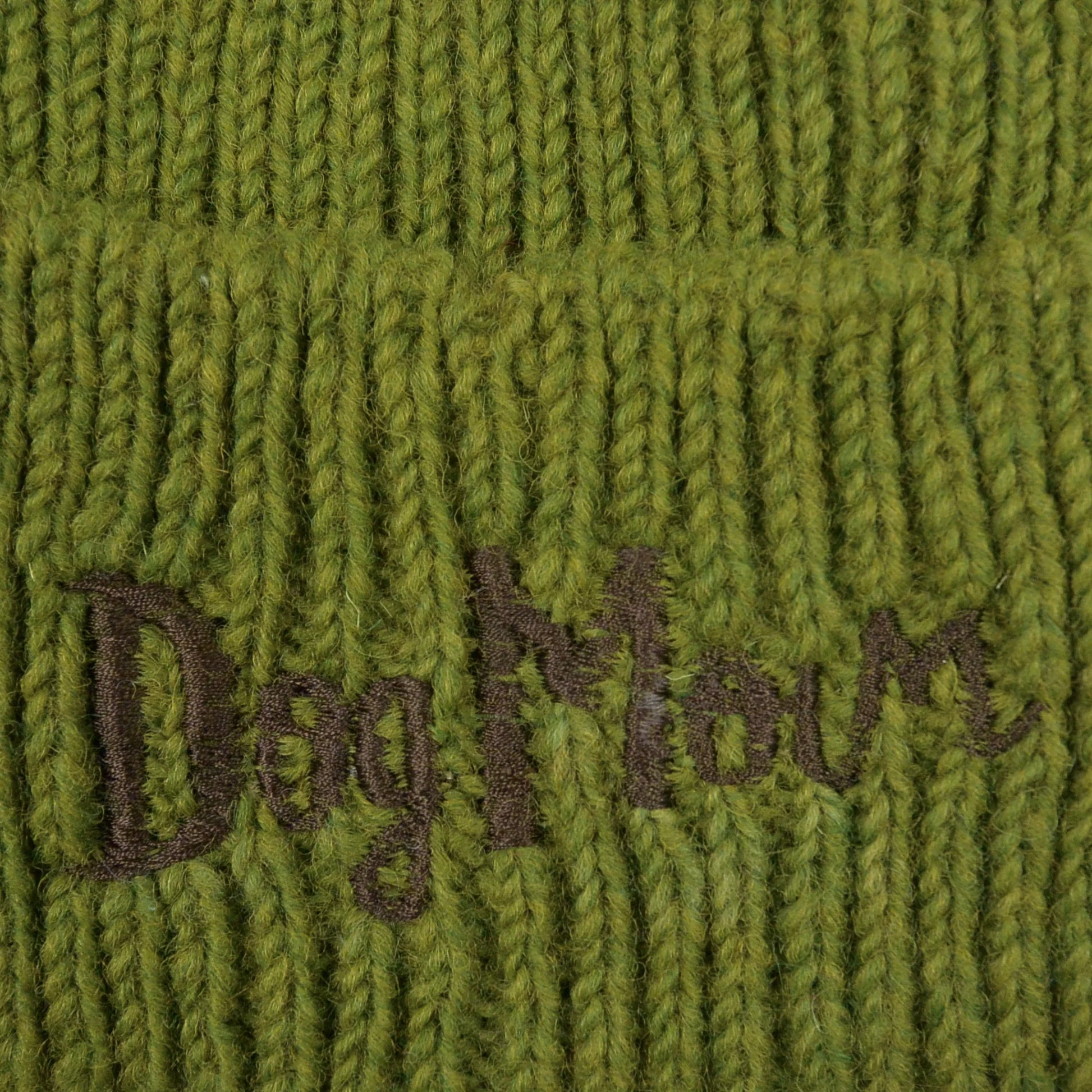 Nahaufnahme von dem gestickten „Dog Mom“-Schriftzug auf Wollmütze, Strickmütze und Beanie-Mütze aus Schurwolle, Grün.