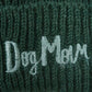 Nahaufnahme von dem gestickten „Dog Mom“-Schriftzug auf Wollmütze, Strickmütze und Beanie-Mütze aus Schurwolle, Dunkelgrün.