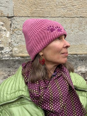 Model präsentiert Wollmütze, Strickmütze, Beanie-Mütze aus Schurwolle, Rosa bestickt mit zwei Pfoten-Logo.