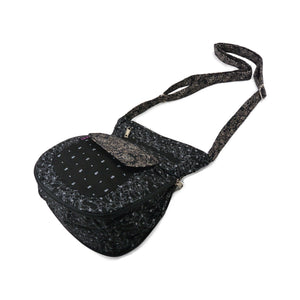 Seitenansicht: Kleine Umhängetasche mit zweiseitigem Design aus Baumwollstoff in Schwarz und Mustermix. Auf beiden Seiten befinden sich zwei Reißverschlussfächer und ein Einsteckfach.
