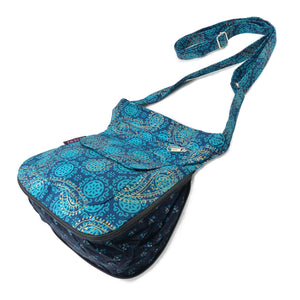 Seitenansicht: Kleine Umhängetasche mit zweiseitigem Design Blumen/Paisley Mustermix aus Baumwollstoff Dunkelblau. Auf beiden Seiten befinden sich zwei Reißverschlussfächer und ein Einsteckfach.