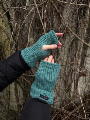 Nahaufnahme Hände: Model präsentiert Handstulpen Mahalaxmi 51 aus Schurwolle mit Fleeceeinlage und Daumenspalte in Türkis.