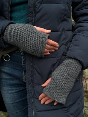 Nahaufnahme Hände: Model präsentiert eine Gürteltasche aus Canvas-Stoff in Dunkelgrau mit Pfoten-Mandala-Stickerei. An den Händen trägt sie Handstulpen MAHALAXMI 54 aus Schurwolle in Grau.