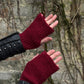 Nahaufnahme von zwei Händen präsentiert Handstulpen, Pulswärmer mit Daumenspalten aus Schurwolle Mahalaxim 55 in Kaminrot.